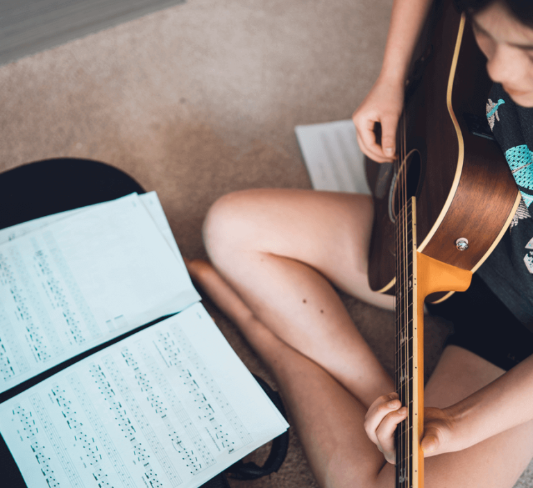 Eurasian Teenage girl practicing music lesson at home on her guitar.