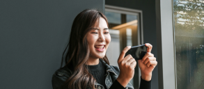 A woman smiling and looking at her phone.