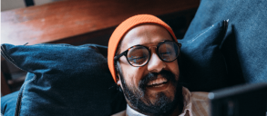 A happy man lying on the couch while playing with this phone.