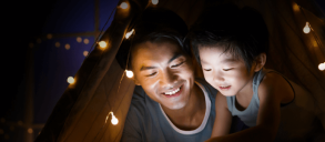 Dad and son looking at a tablet inside an indoor play tent.