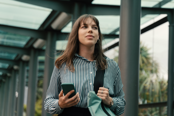 A woman walking while holding her phone.